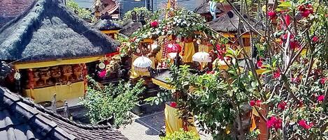 Ein traditionelles Gebäude mit einem strohgedeckten Dach, umgeben von üppiger Vegetation und blühenden Pflanzen.