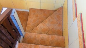 A staircase with orange patterned tiles and a wooden handrail. - Arjuna Homestay Ubud (Ubud)
