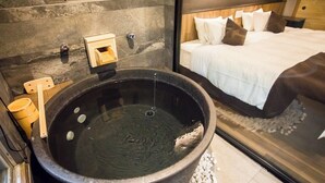 Een badkamer met een groot zwart bad, een houten emmer en een klein houten doosje.