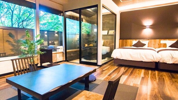 Een moderne slaapkamer met een groot bed, een eettafel en een schuifglazen deur die uitkomt op een balkon.