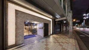 Entrada de un hotel con un diseño de luces a cuadros, alfombra azul y suelo de baldosas.
