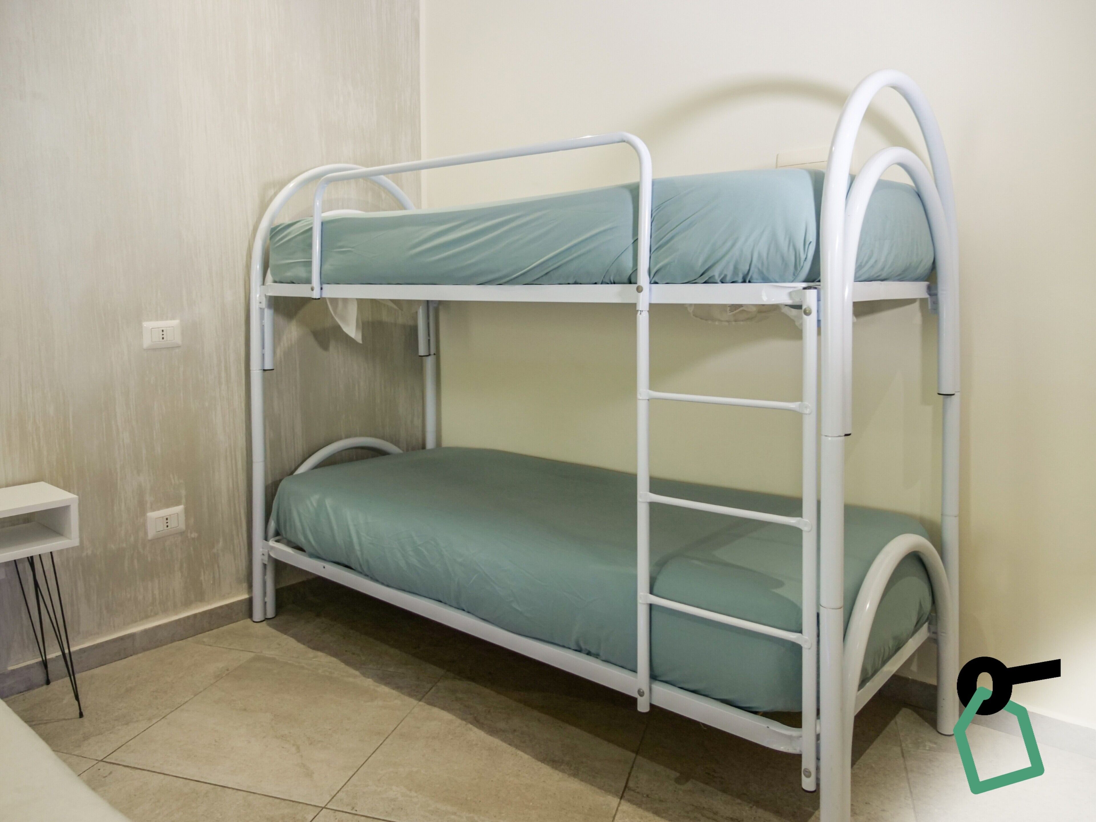 A bunk bed in a room with a small white table and a wall socket.