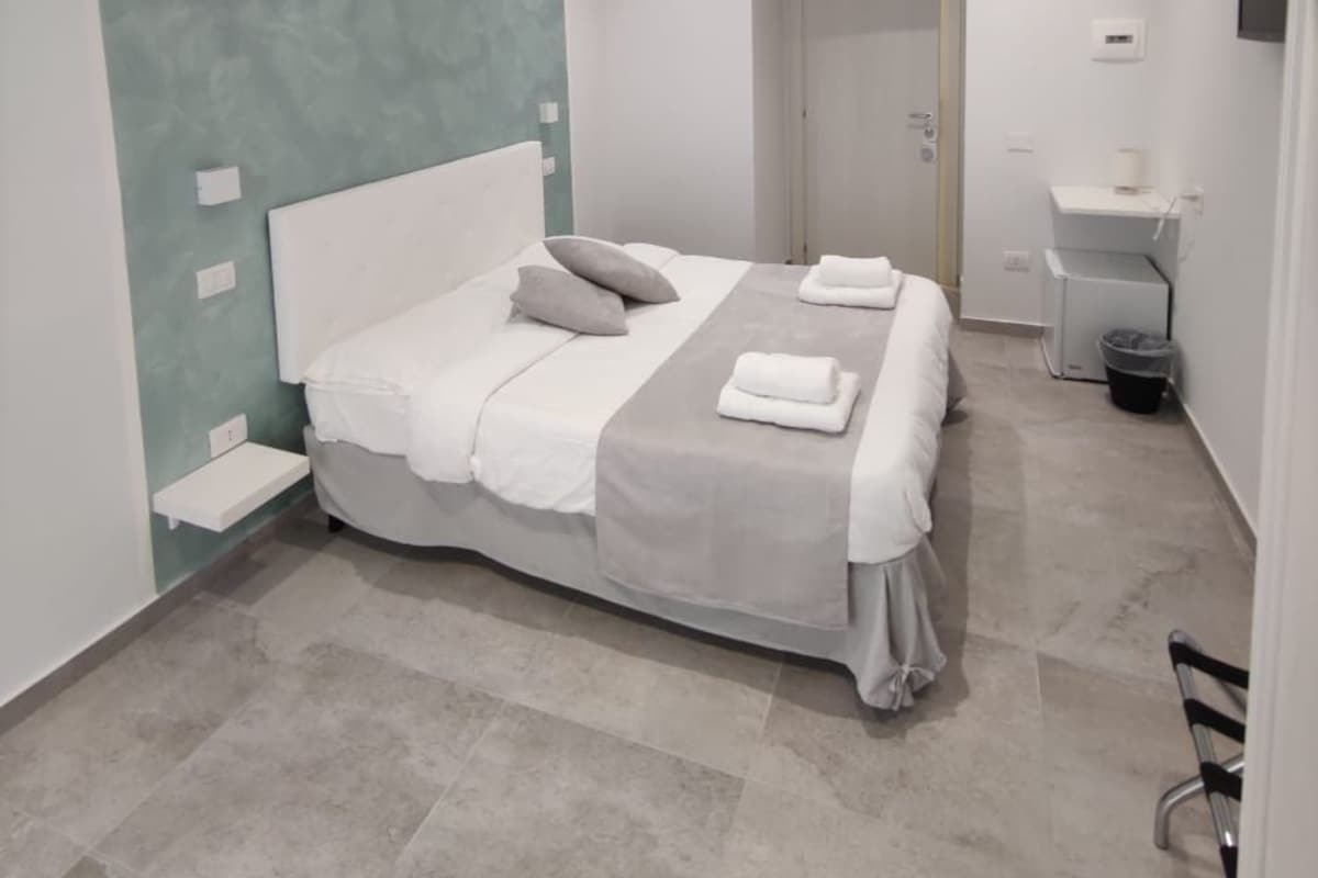 A modern bedroom with a bed, bedside tables, a nightstand, and a wall-mounted TV.