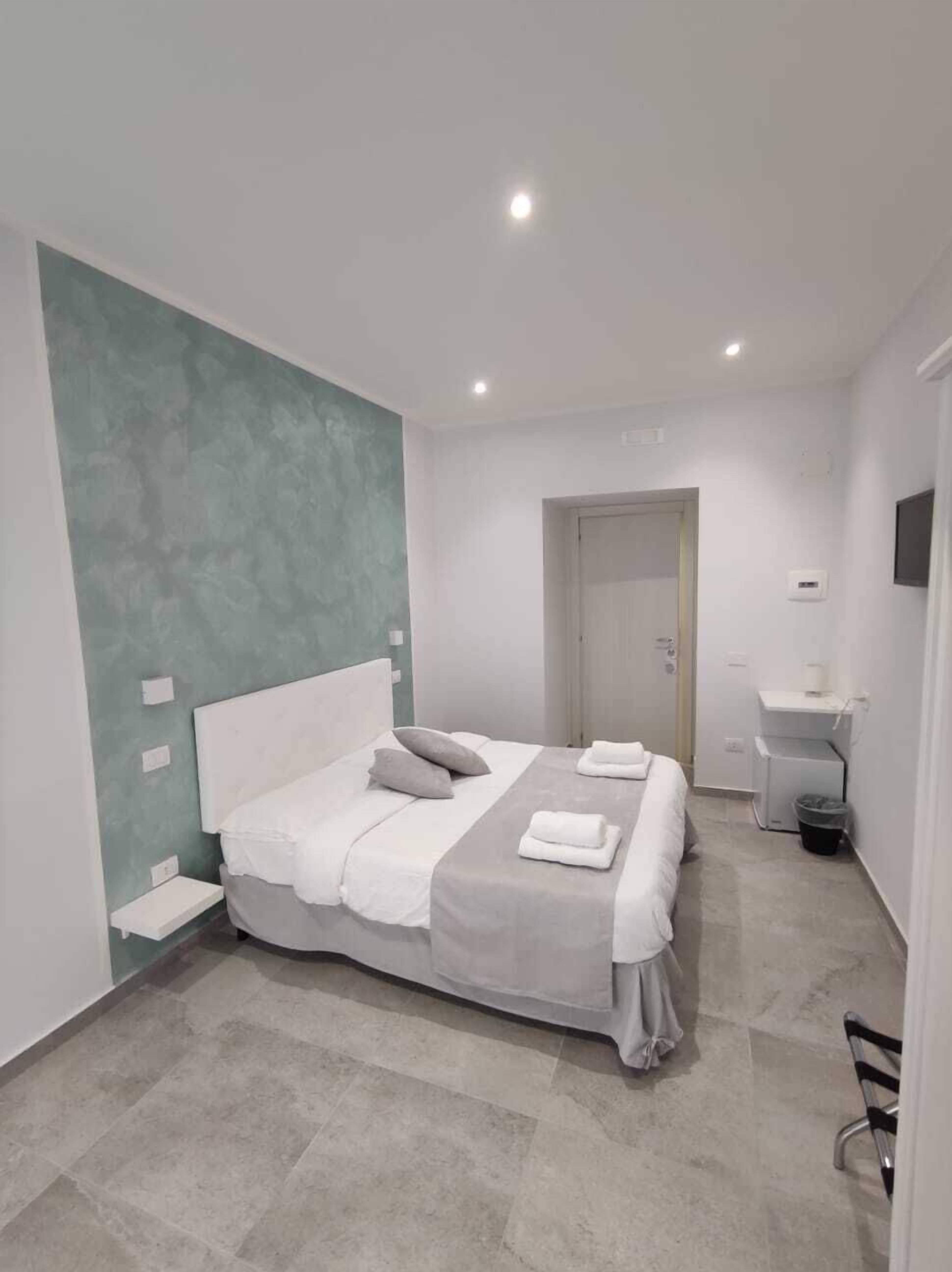 A modern bedroom with a bed, bedside tables, a nightstand, and a wall-mounted TV.