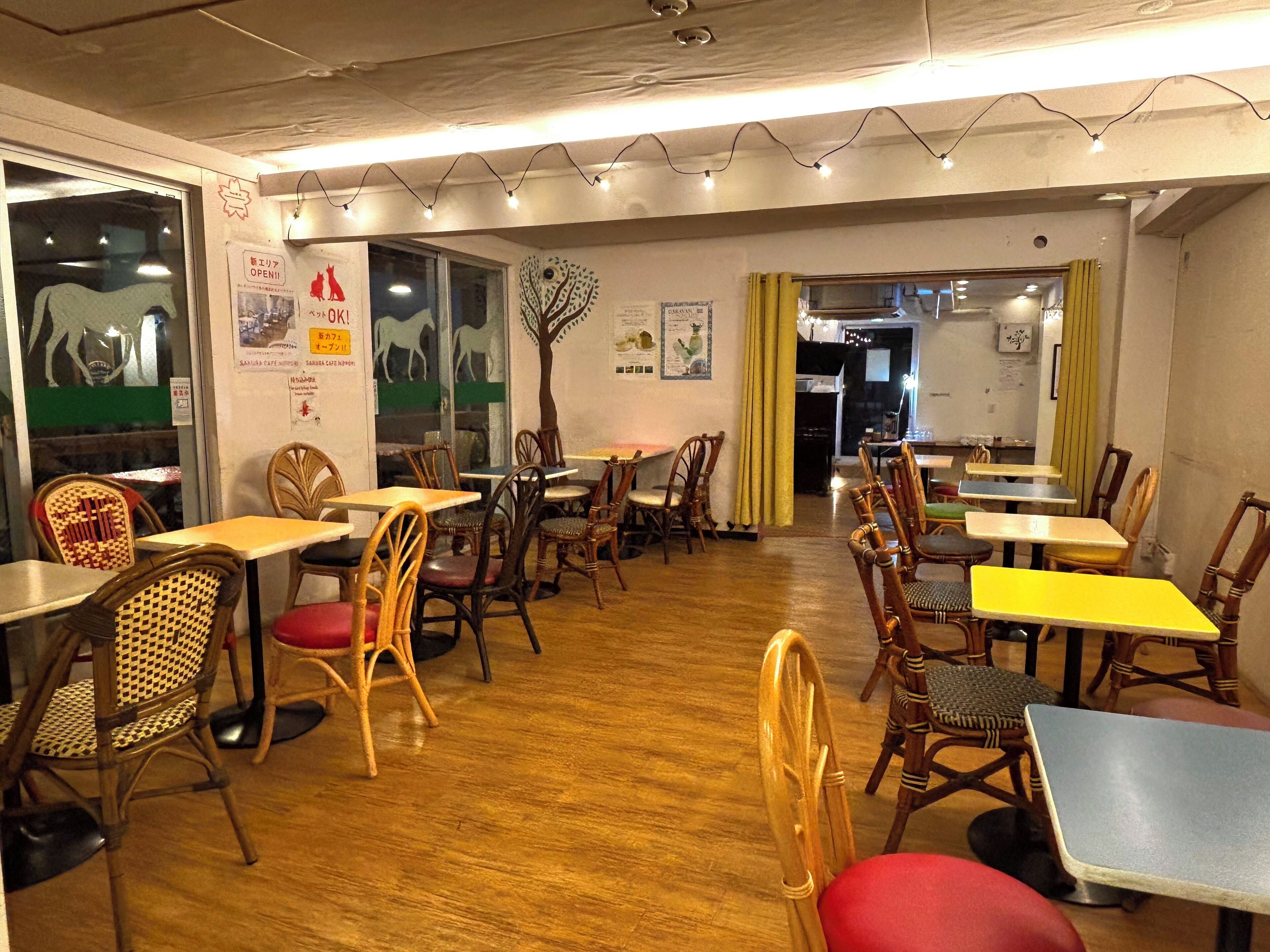 Un espace de restauration intérieur avec des tables et des chaises en bois, une fresque représentant un arbre sur le mur et un panneau indiquant que le restaurant est ouvert.
