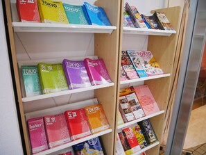 A shelf with various travel guides and maps for Tokyo. - Sakura Hotel Nippori (Tokyo)
