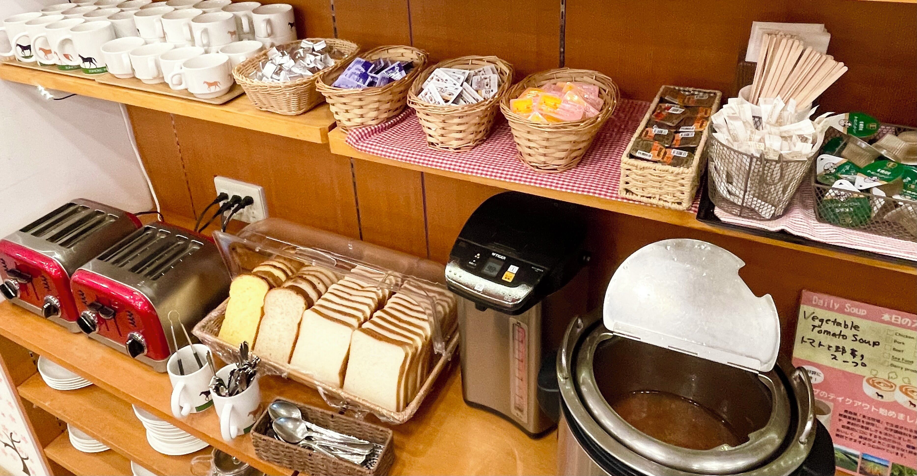 A breakfast setup with various food items and utensils, including bread, tea, and a coffee machine.