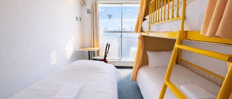 Habitación de hotel con dos camas, ventana con vista a la ciudad, aire acondicionado y una silla.