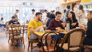 Un comedor interior concurrido, con sillas y mesas de madera, un menú visible y un letrero que anuncia la selección de cervezas.