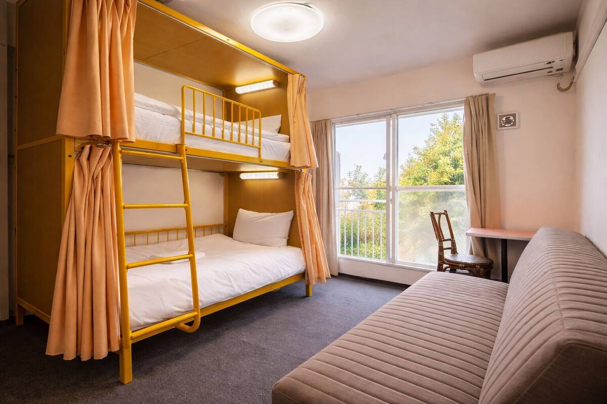 A bunk bed room with a balcony, a sofa, and an air conditioning unit.