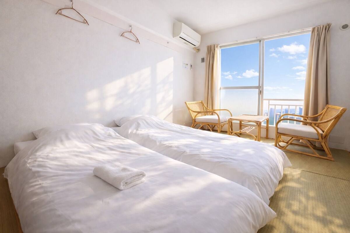 A hotel room with a large bed, two chairs, a small table, and a window with a view.