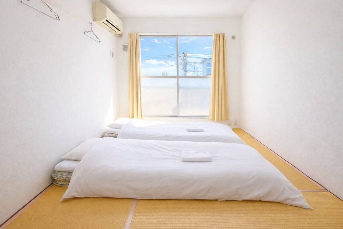 A hotel room with two beds, a large window with curtains, and a view of the sea.