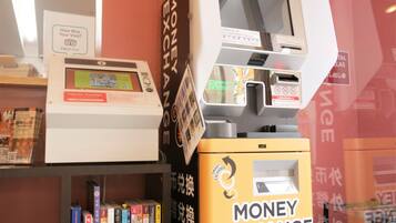 A currency exchange machine with a digital display and a keypad, surrounded by books and informational posters.