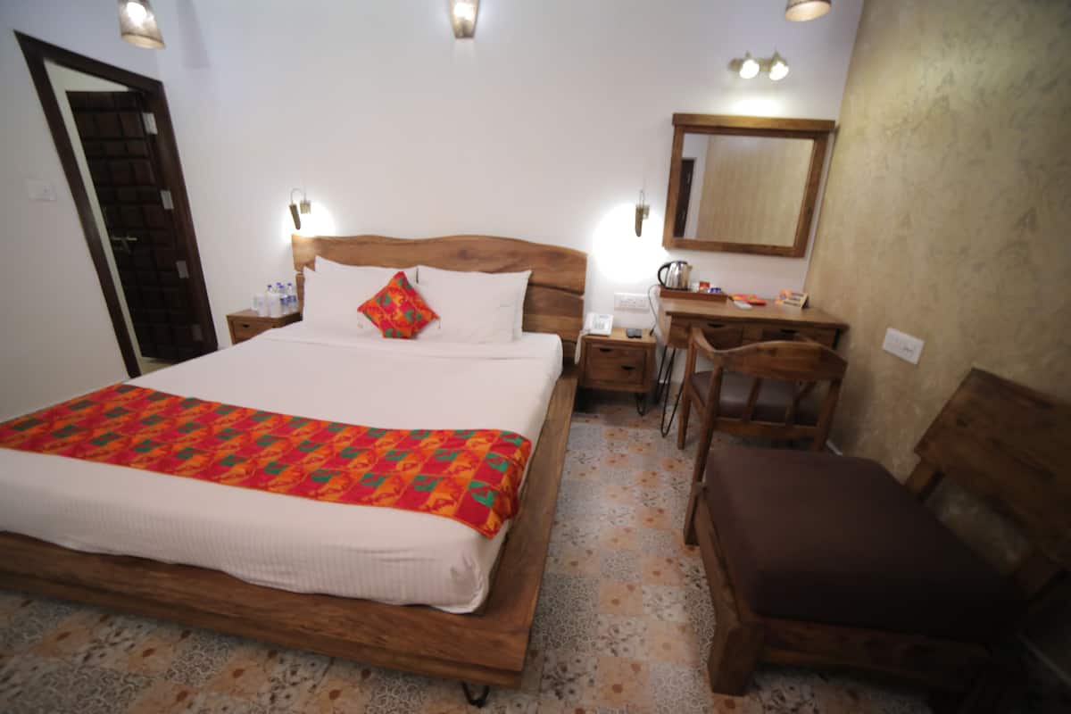 A bedroom with a wooden bed, bedside tables, a desk, and a chair.