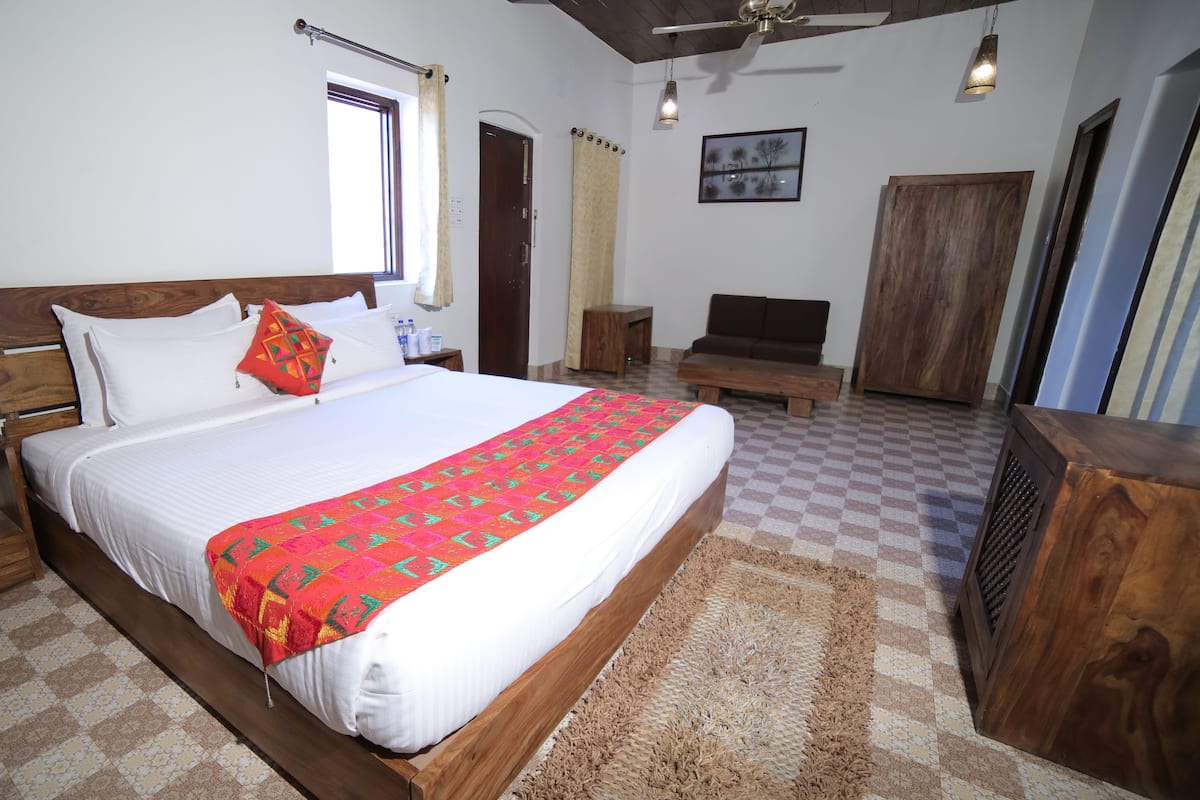A hotel room with a large bed, wooden headboard, a telephone, and a bedside table.