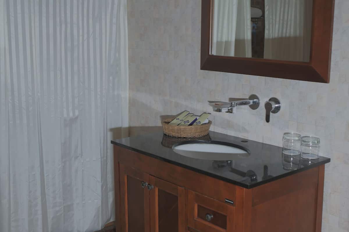 A bathroom with a wooden vanity, a mirror, and a shower curtain.