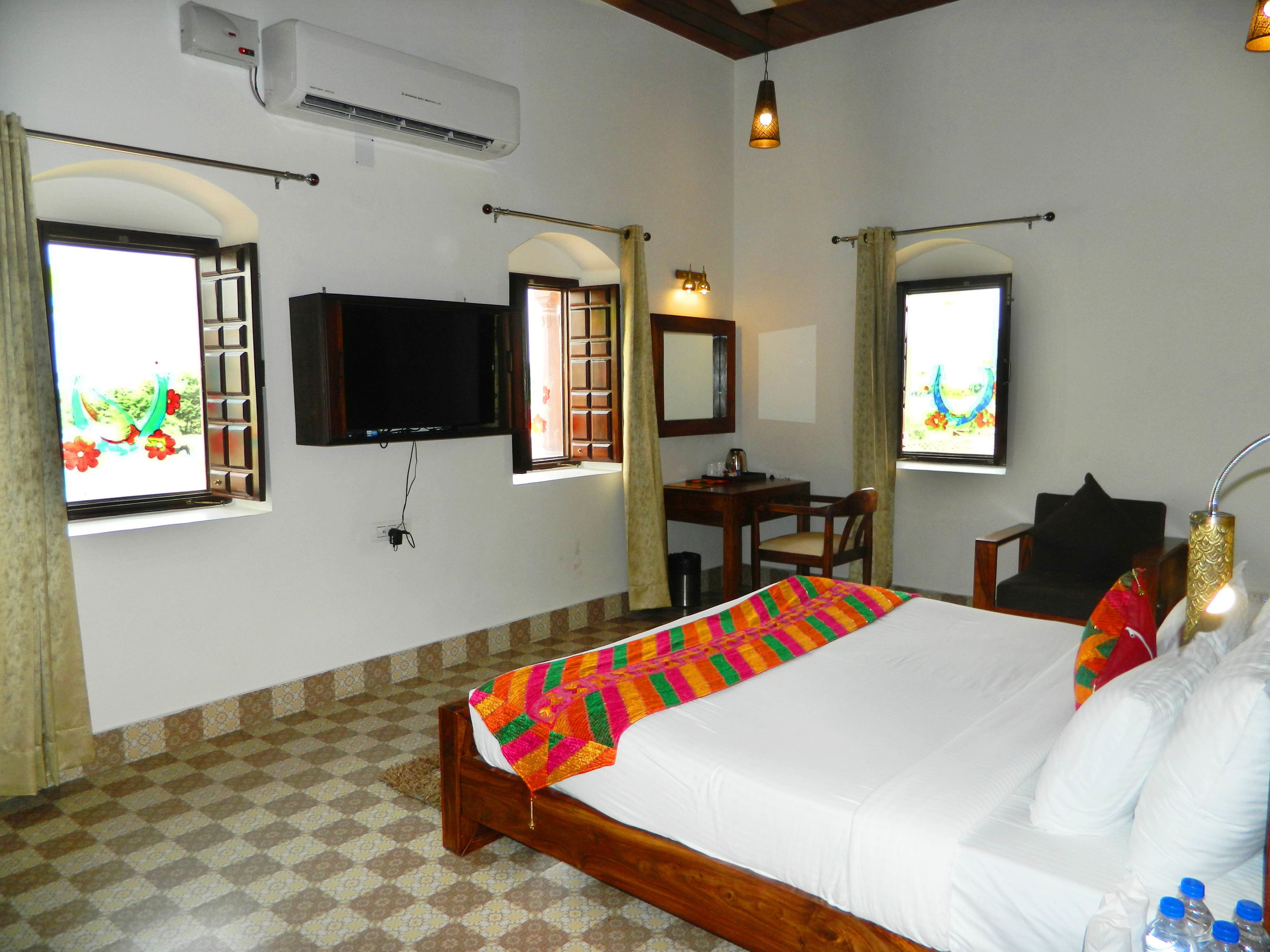 A hotel room with a bed, a desk, a chair, and a television.