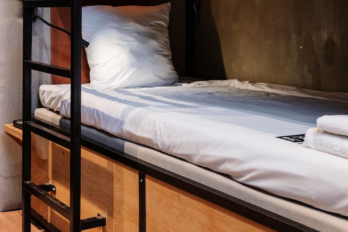 A bunk bed with a ladder, white bedding, and a wooden headboard.