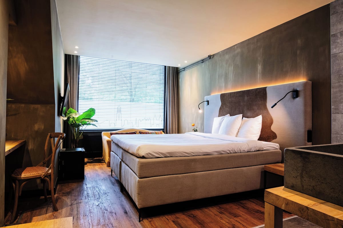 A modern bedroom with a large bed, a desk, and a chair.