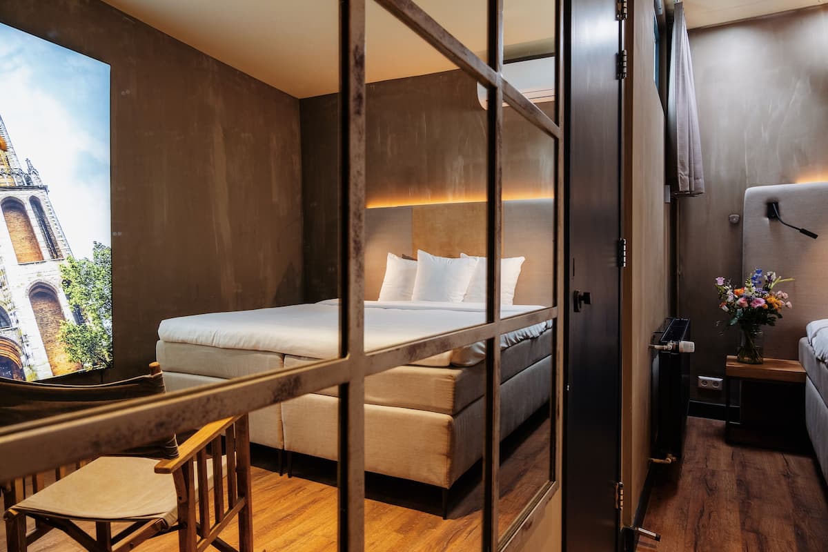A hotel room with a bed, a desk, a chair, and a television displaying a cityscape.