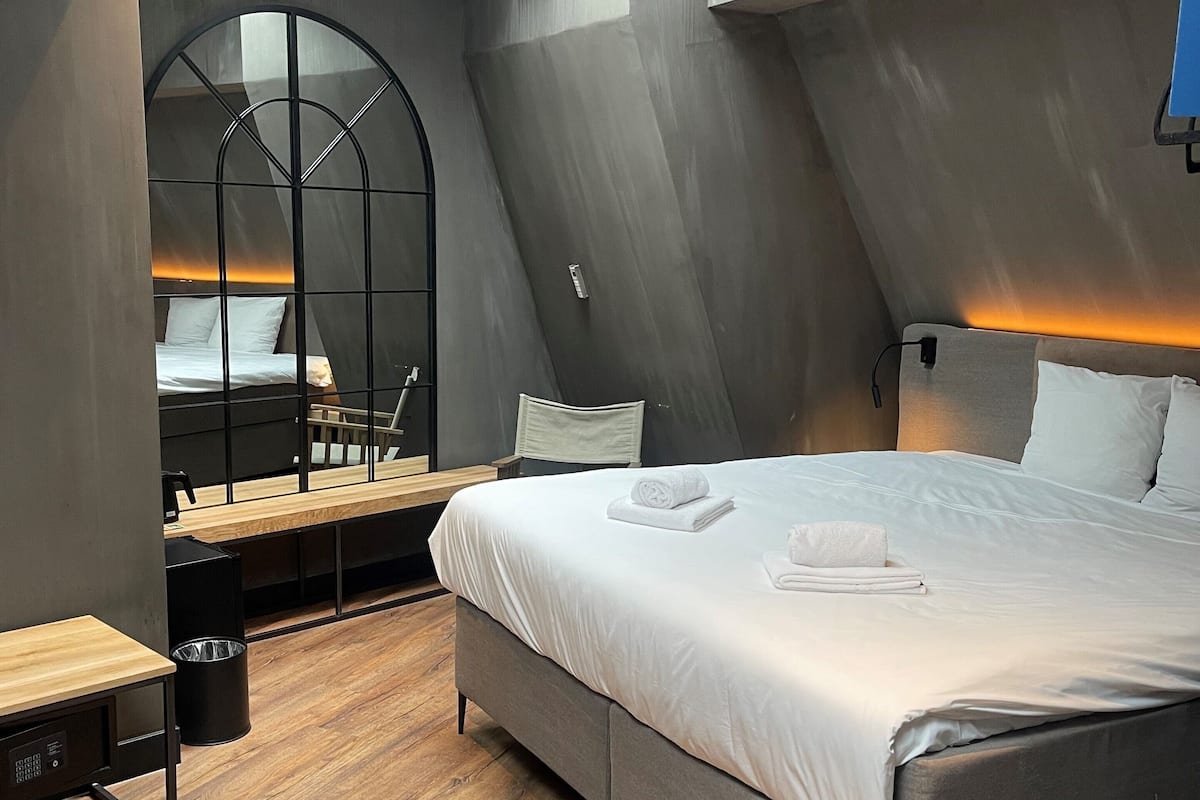 A modern bedroom with a skylight, a bed, a desk, and a chair.