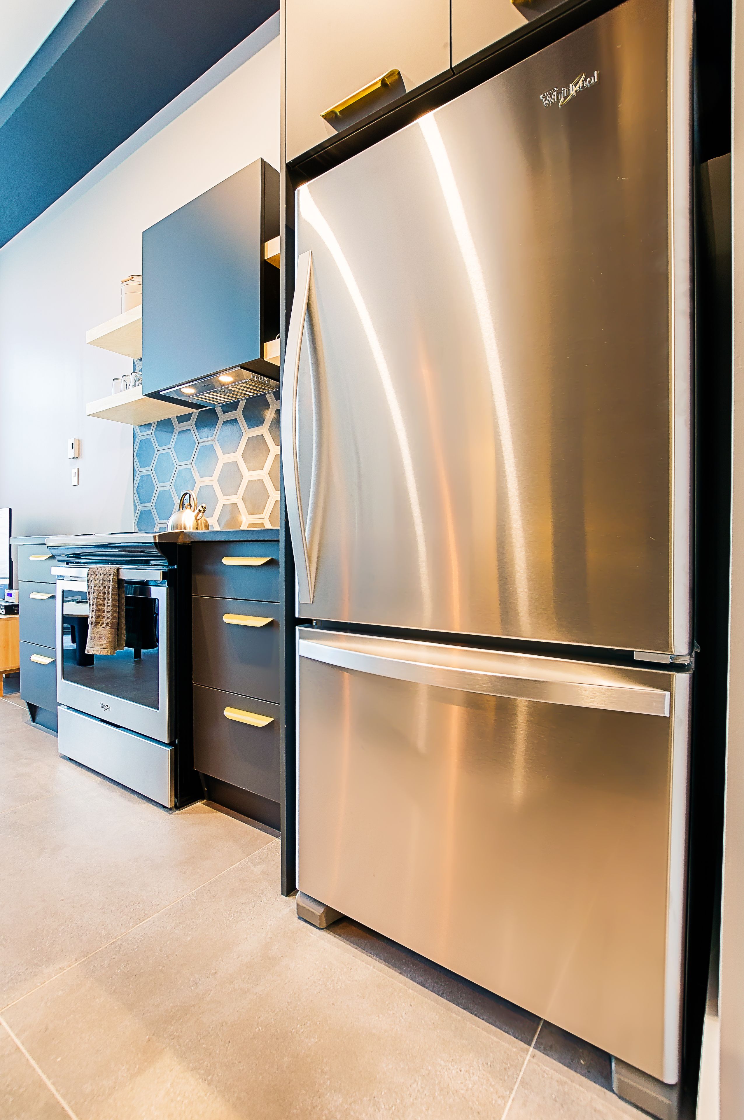Una cocina moderna con electrodomésticos de acero inoxidable, horno empotrado y salpicadero de forma hexagonal.