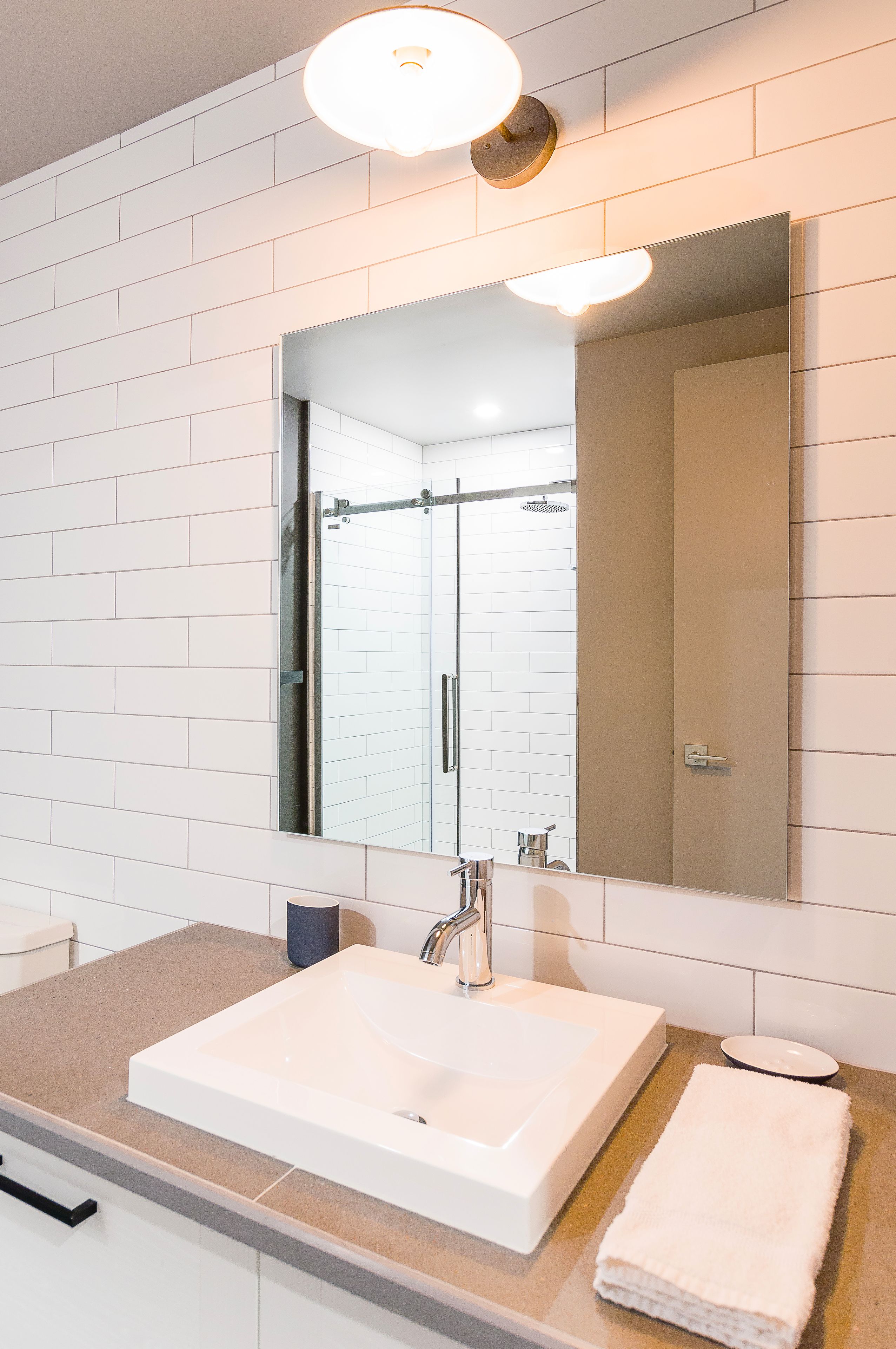 Un bany modern amb un lavabo blanc, un mirall gran i una porta de dutxa de vidre.