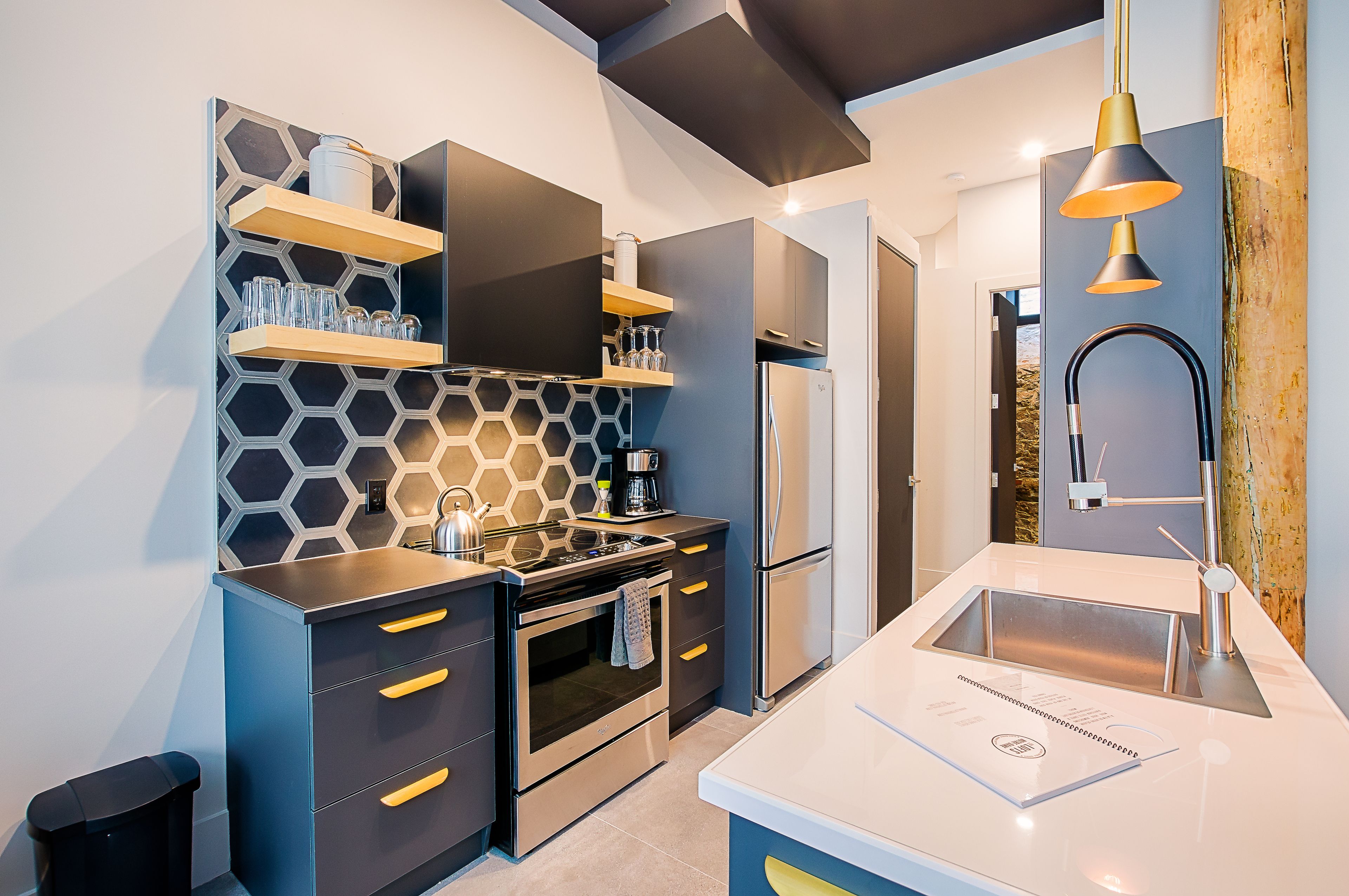A modern kitchen with a stainless steel refrigerator, a built-in oven, and a sink with a contemporary faucet.