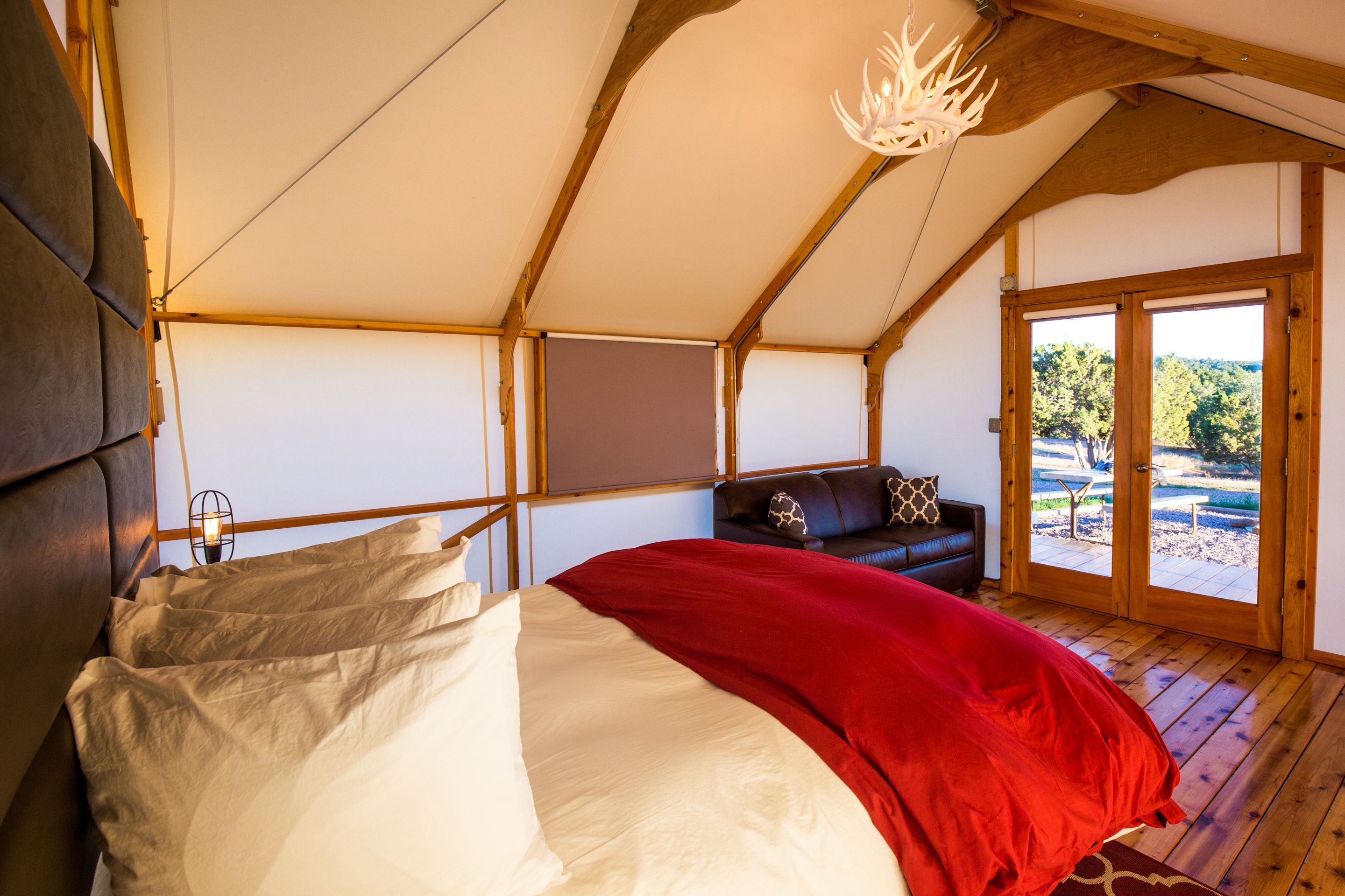 Una habitación tipo tienda con una cama, un sofá y un ventanal grande.