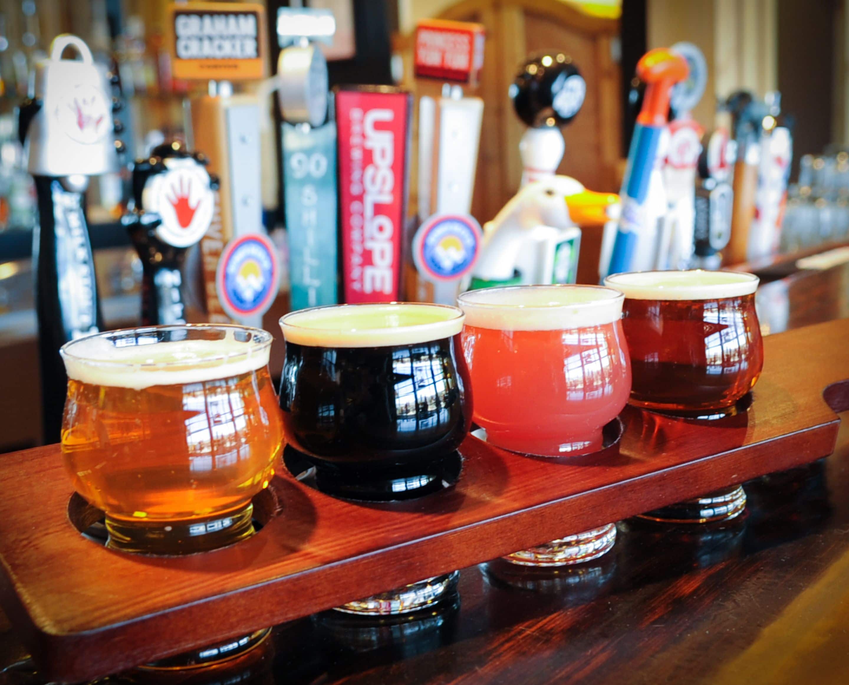 Een bar met verschillende bierglazen op een houten toonbank.