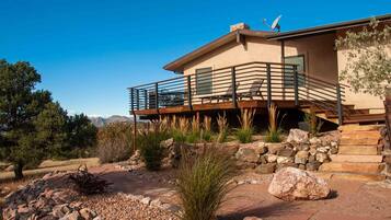 A modern house with a balcony, stone steps, and a landscaped garden.