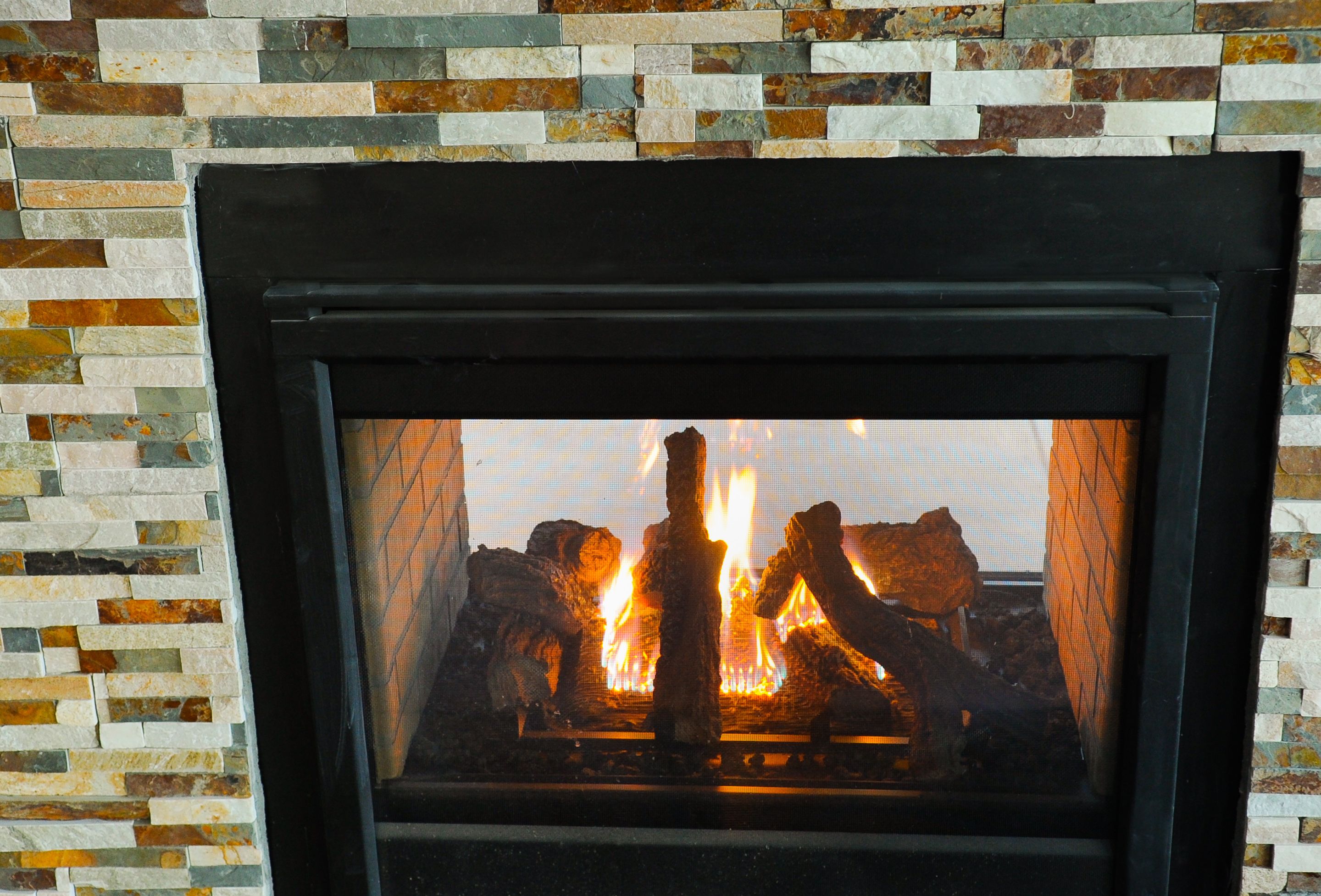 A fireplace with a stone mosaic surround.