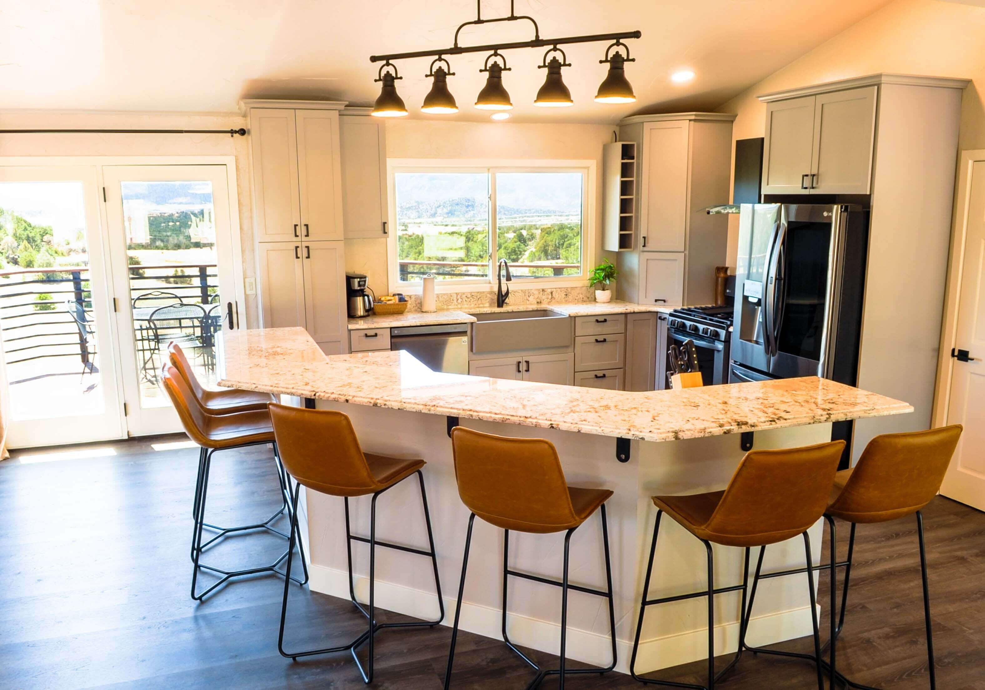A modern kitchen with a large island, bar stools, and a view of the outdoors.