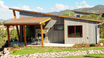 A modern house with a patio, stone fireplace, and a view of the mountains.