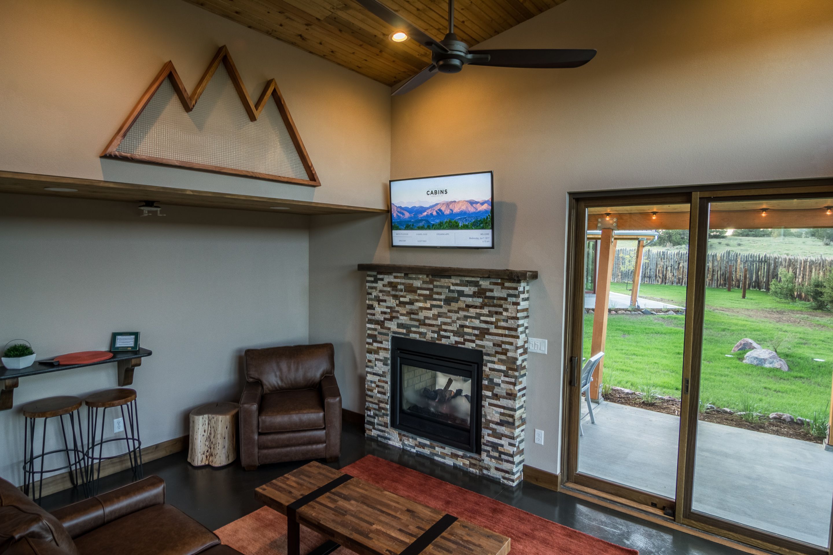 Una sala de estar moderna con chimenea de piedra, muebles de cuero y un ventanal con vistas al exterior.