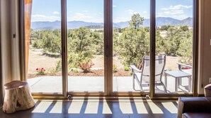 A room with large sliding glass doors leading to an outdoor patio with a table and chairs. - Royal Gorge Cabins (Canon City)