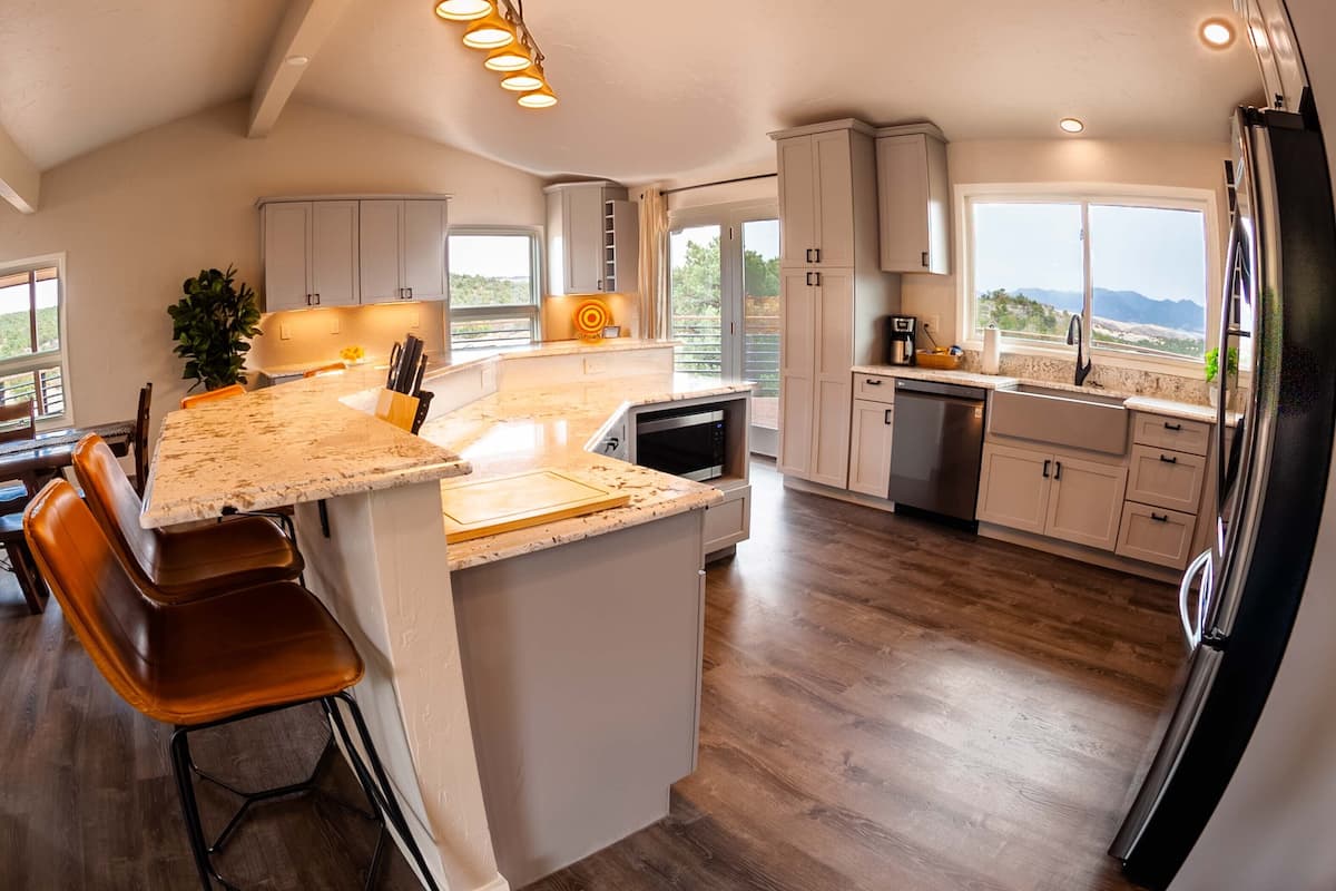 Uma cozinha moderna com uma ilha grande, banquetas e vista para o exterior.