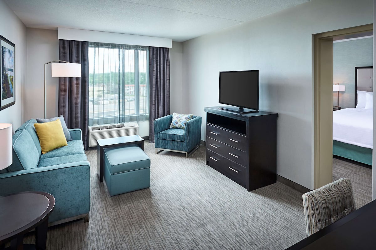 Ein Hotelzimmer mit Sofa, Sessel, Fernseher und Bett.