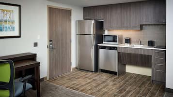 Cozinha moderna com frigorífico, micro-ondas, máquina de café e máquina de lavar loiça.