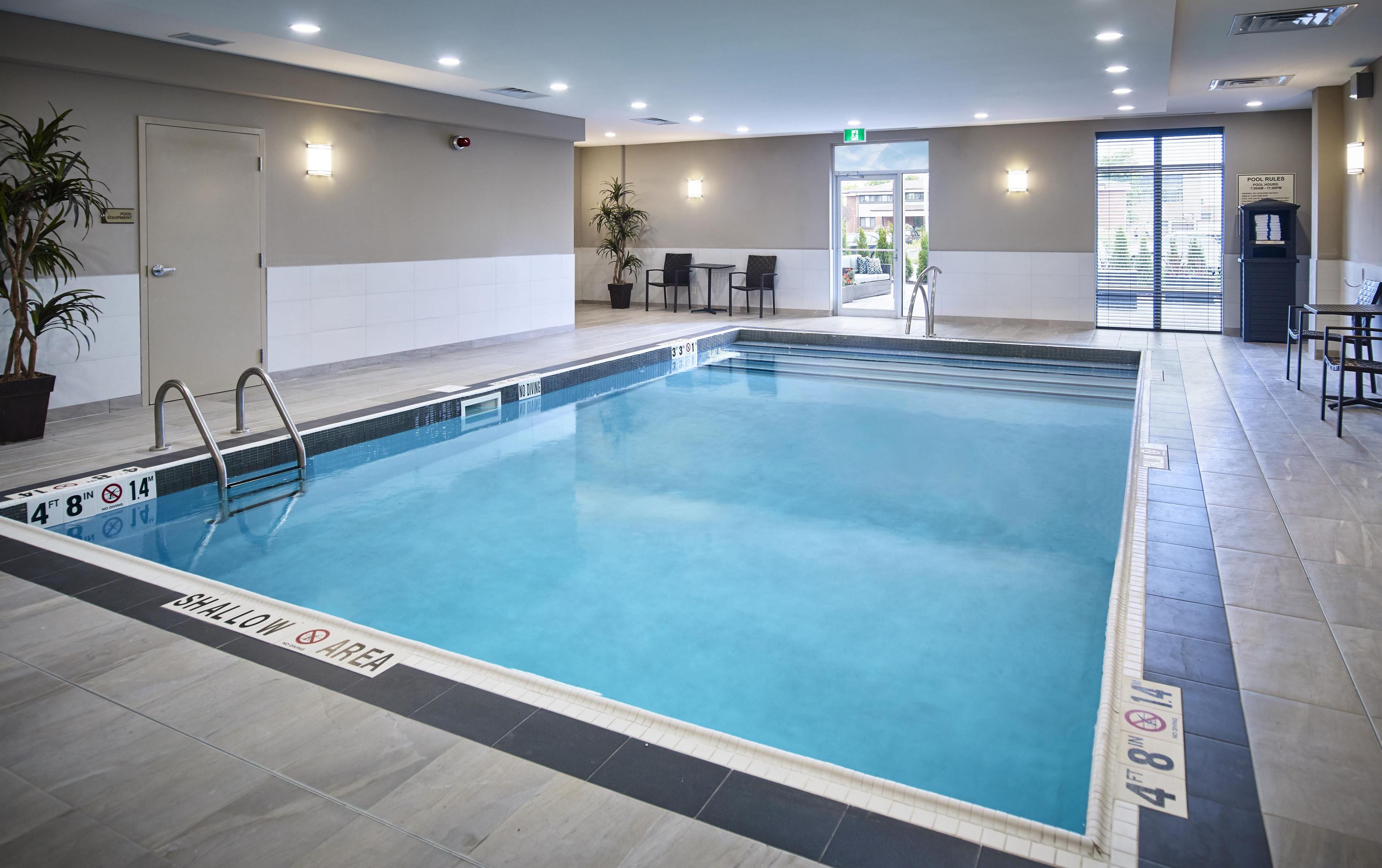 Ein Hallenbad mit klarem Wasser, Tiefenlinien und einem Hinweis auf den flachen Bereich.