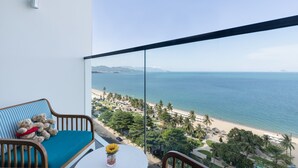 A balcony with a view of a beach, a sofa, and a small table with a vase. - Citadines Bayfront Nha Trang (Nha Trang)