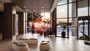 A modern lobby with large windows, seating areas, and a view of the sunset. - Citadines Bayfront Nha Trang (Nha Trang)