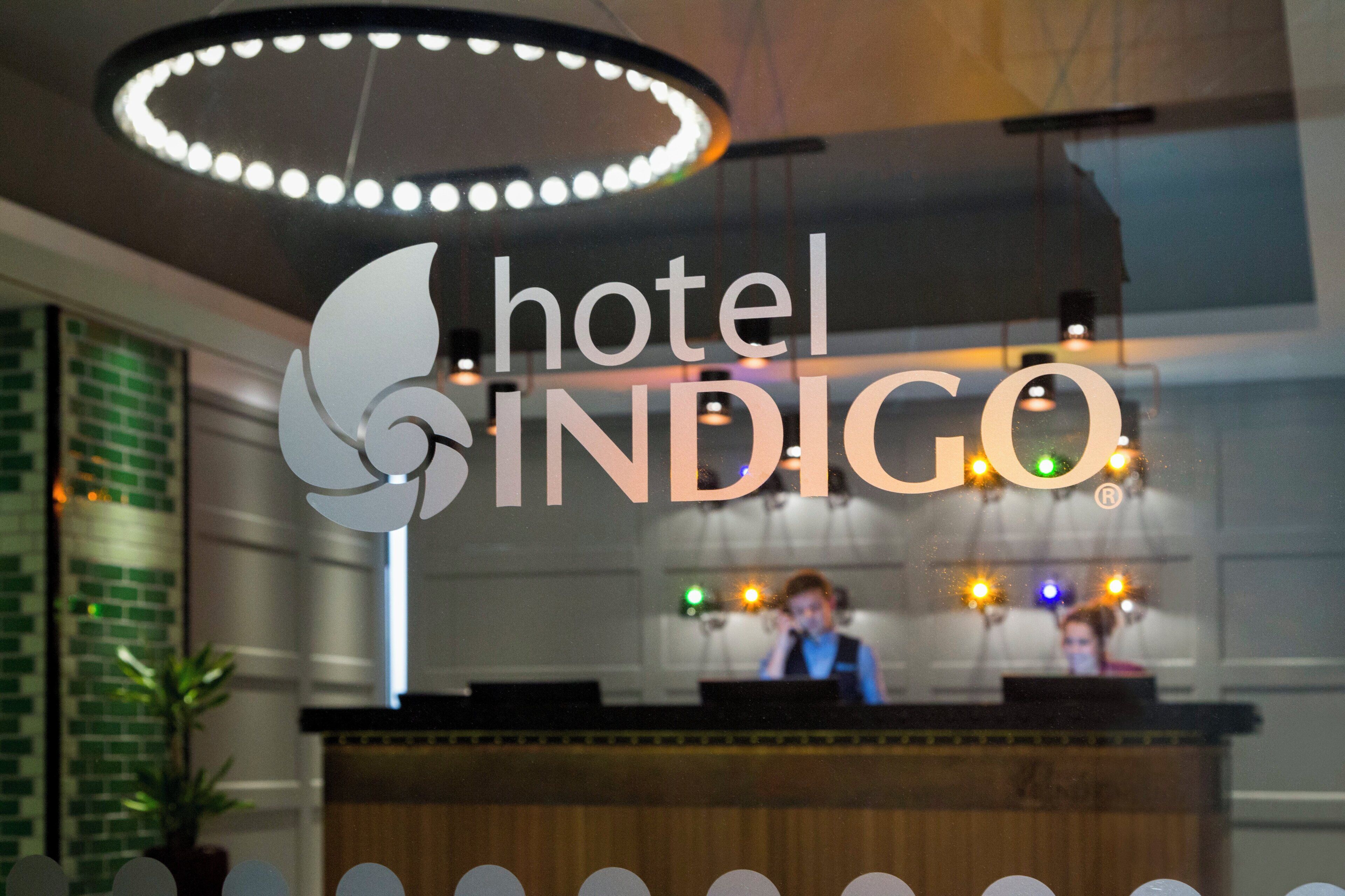 En hotellreception med en logotyp och en modern lampa ovanför.