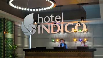 En hotellreception med en logotyp och en modern lampa ovanför.