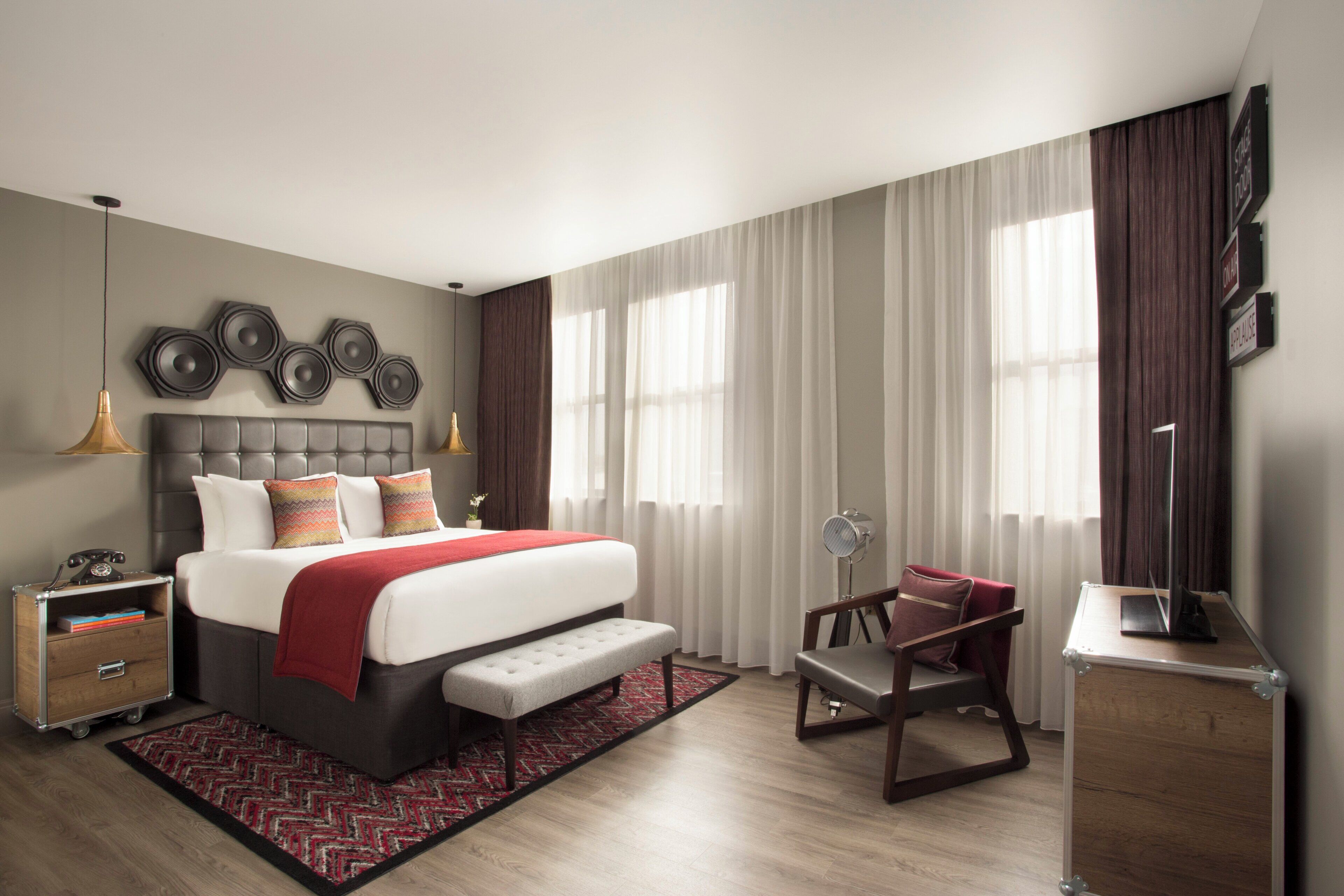 A modern hotel room with a large bed, bedside tables, a desk, and a chair.
