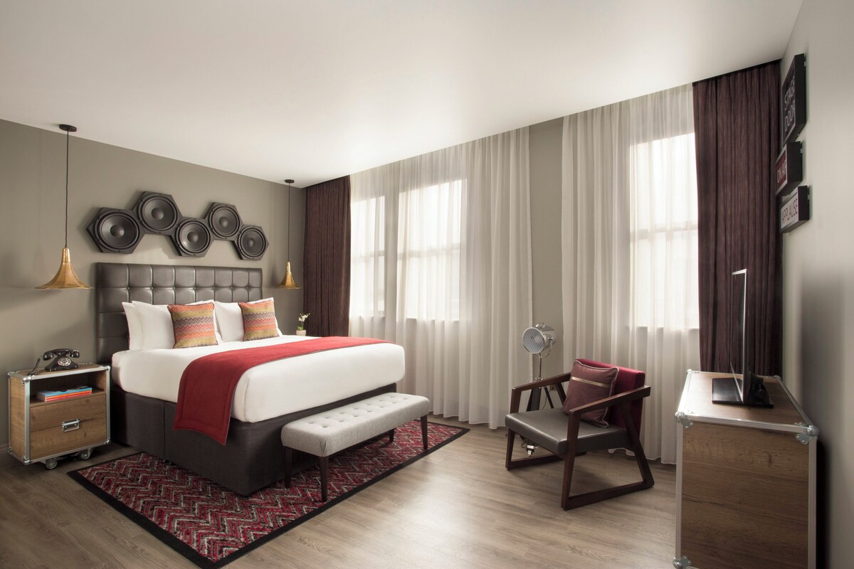 Una moderna camera d'albergo con un letto grande, comodini, una scrivania e una sedia.