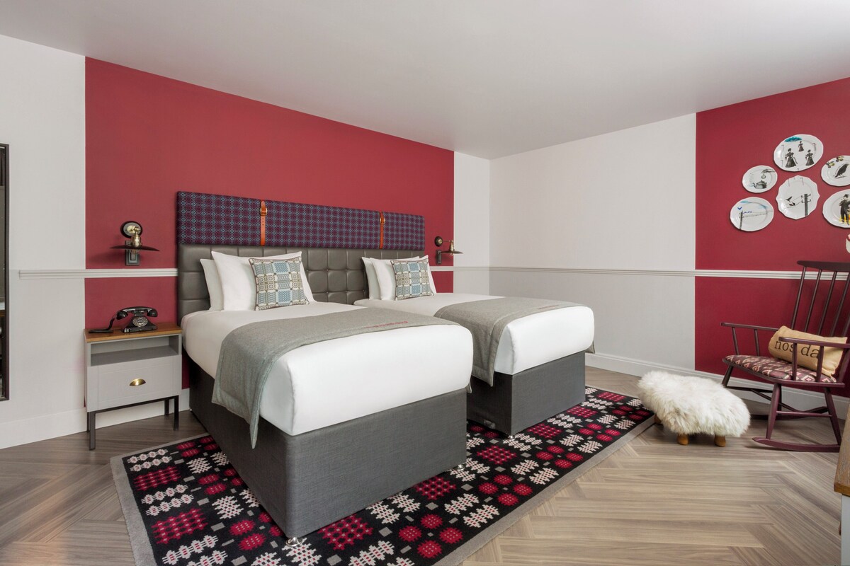 Una camera da letto con un letto matrimoniale, un comodino, una sedia e una sveglia a muro.