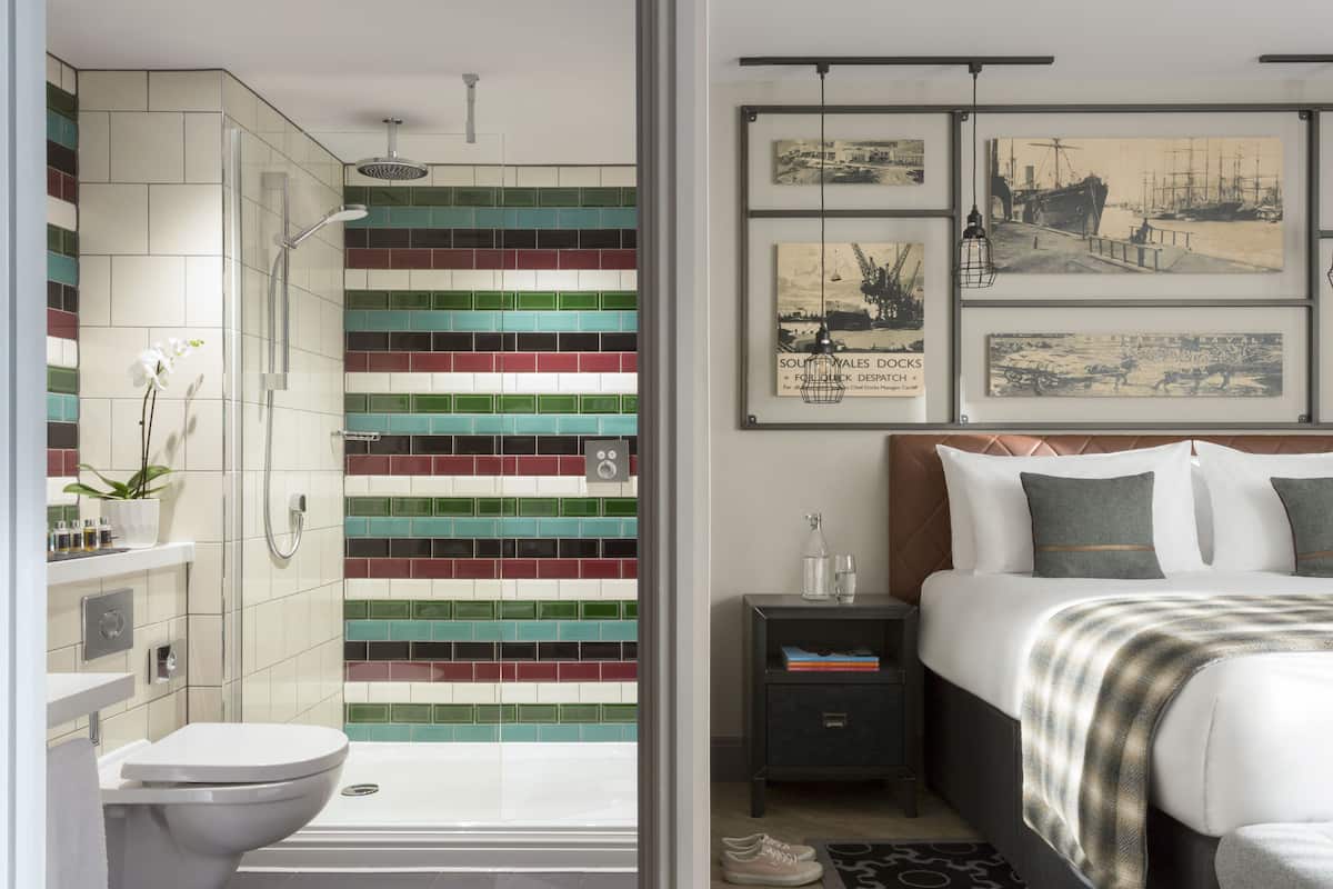 A modern bathroom with a shower, toilet, and a tiled wall with a colorful pattern.