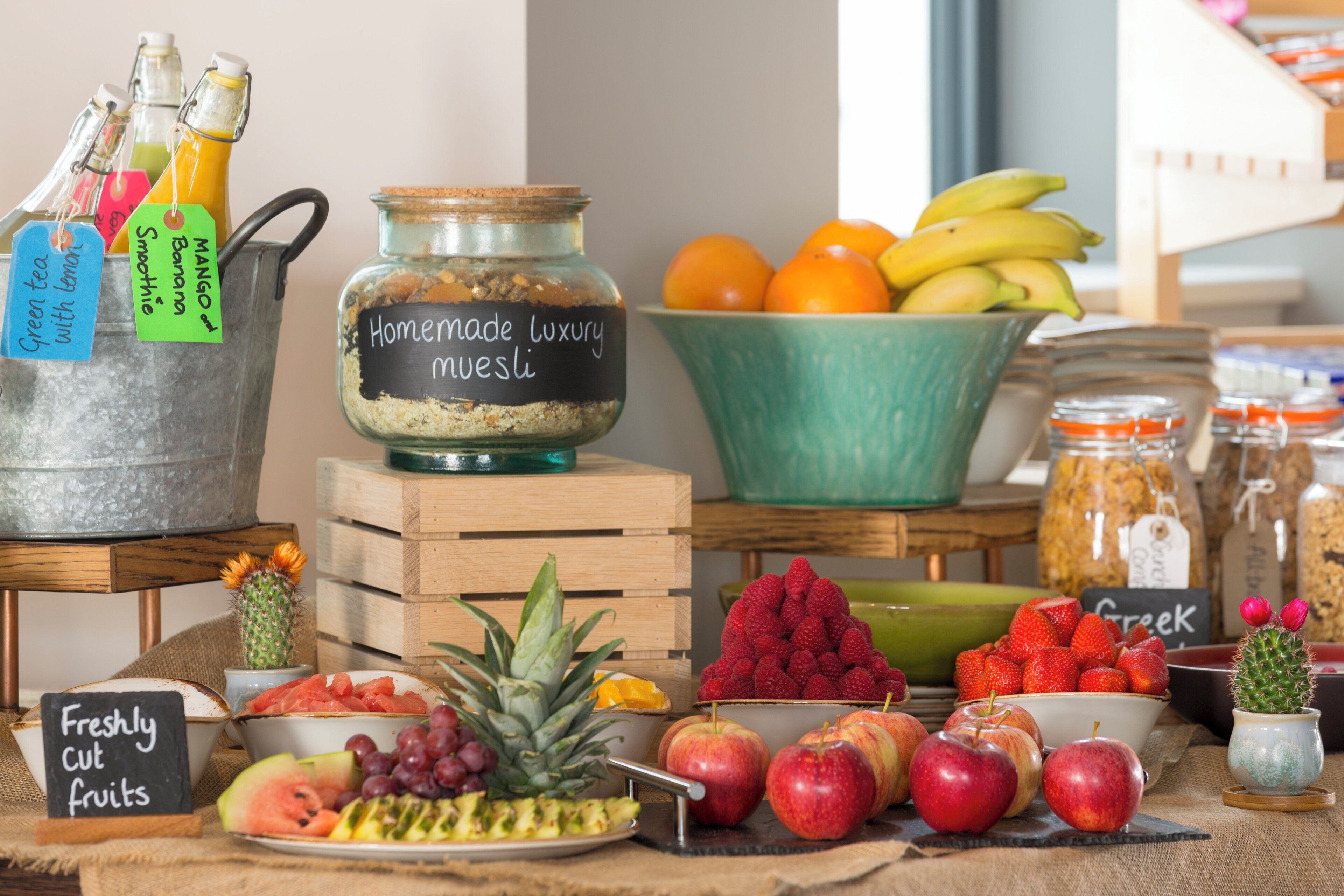 A variety of fresh fruits and homemade luxury muesli displayed on a wooden table.