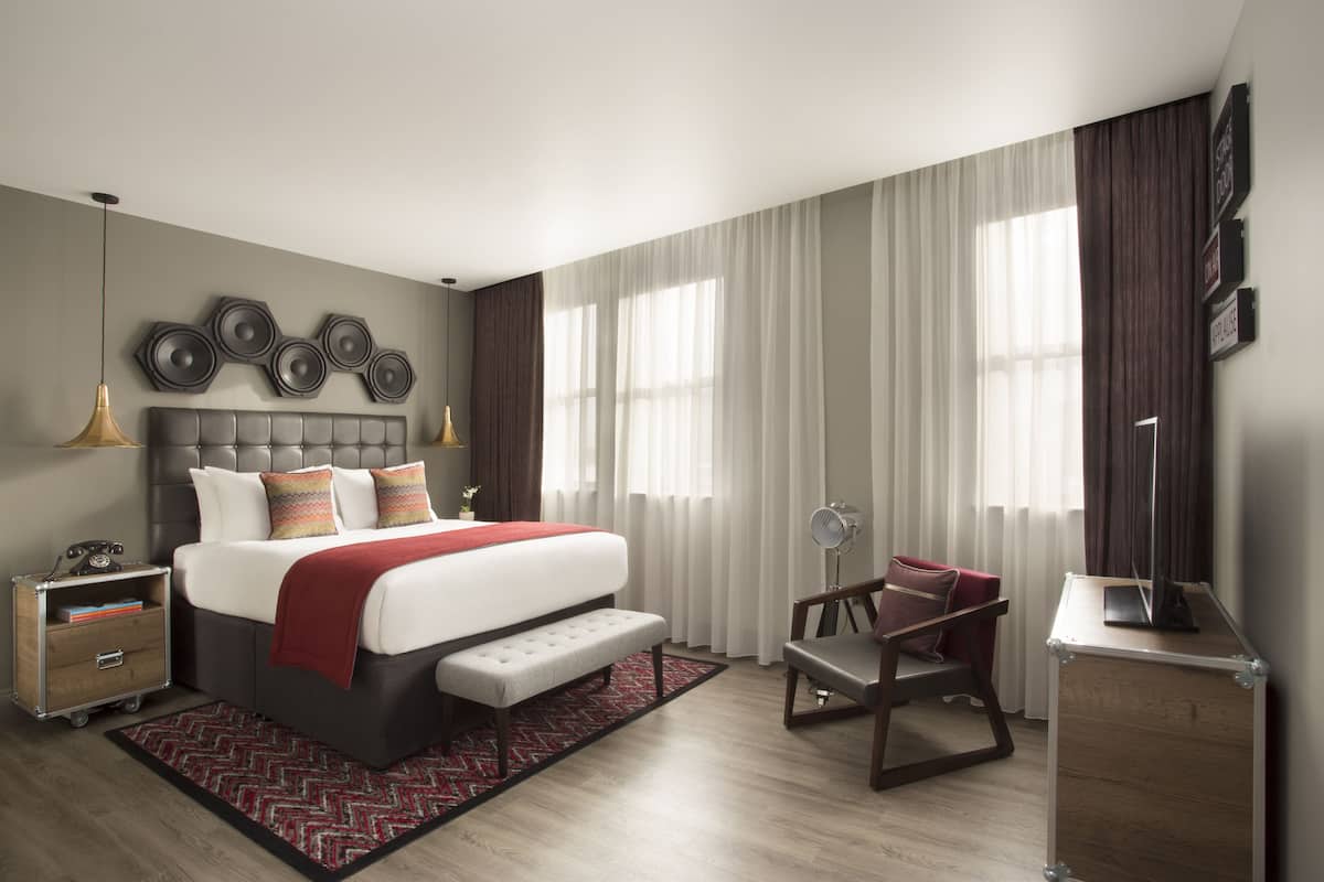 A modern bedroom with a large bed, bedside tables, a desk, and a chair.